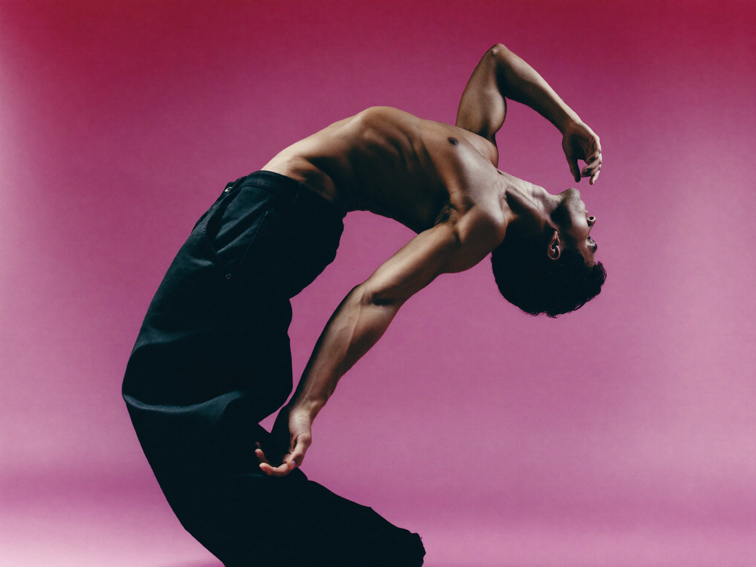 Una persona arqueando la espalda en un movimiento de danza sobre fondo rosa